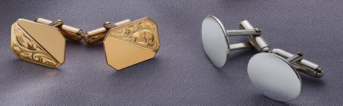 A pair of 9ct yellow gold cufflinks that have been engraved on half of their surface and a pair of sterling silver oval cufflinks with a plain design, both an a light grey satin background