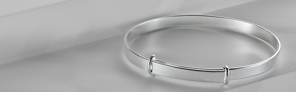 Sterling Silver expandable christening bangle lying on a white jewellery display pedestal