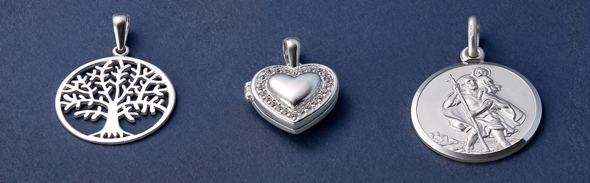 2 Sterling Silver Religious Pendants and a Shimmering CZ studded Silver Heart Shaped Locket on a blue background